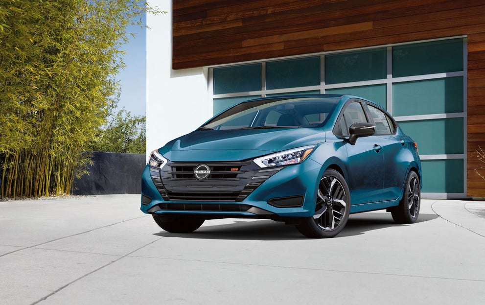 2025 Nissan Versa parked in a driveway in front of a modern garage
